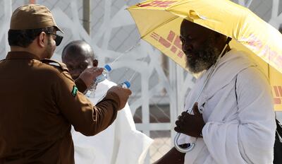 A Saudi soldier sprinkles water on pilgrims to cool them off as they walk to pray at Mount Arafat during Hajj. EPA