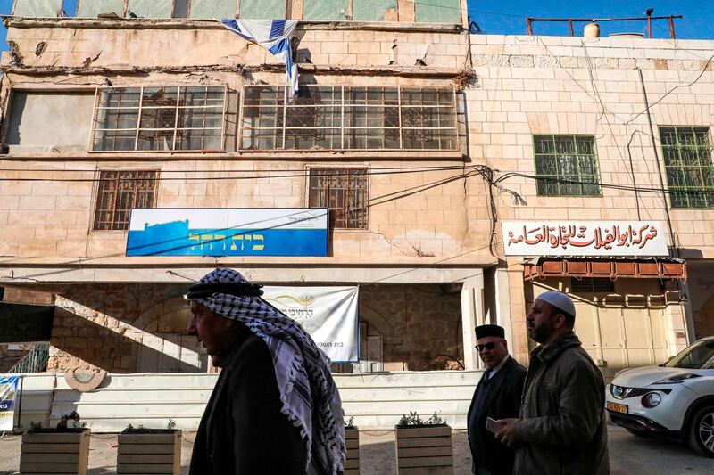 Palestinian men walk past a building occupied by Israeli settlers bearing a sign reading in Hebrew "Beit Rachel" near the old city of the flashpoint city of Hebron in the occupied West Bank. AFP