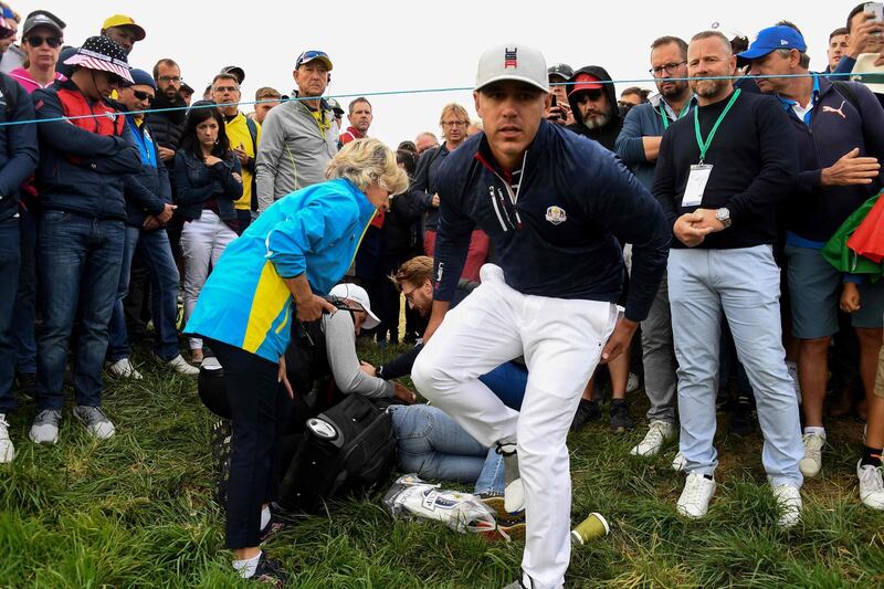TOPSHOT - US golfer Brooks Koepka (R) reacts next to an injured spectator who fell  during the fourball match on the first day of the 42nd Ryder Cup at Le Golf National Course at Saint-Quentin-en-Yvelines, south-west of Paris on September 28, 2018.  / AFP / FRANCK FIFE
