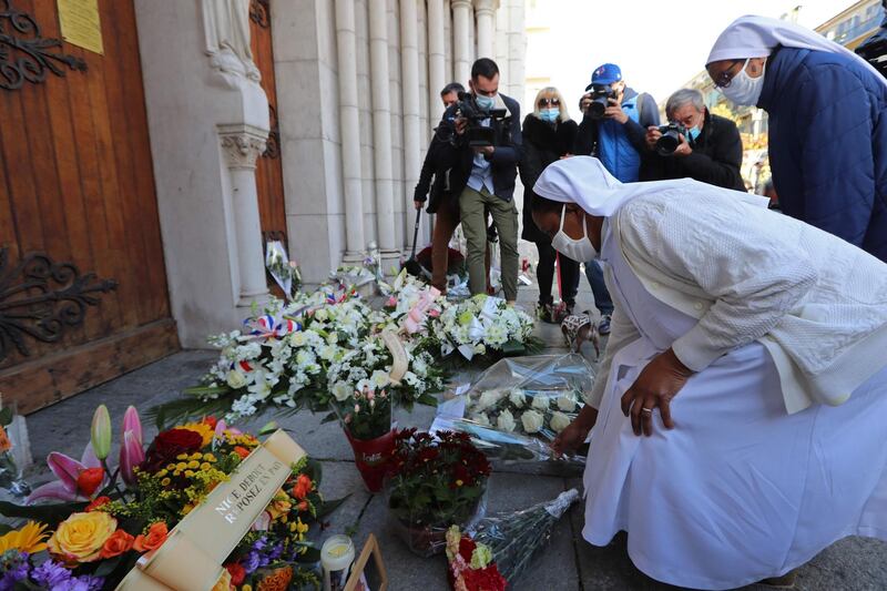 Two nuns lay flowers in front of the church in Nice. AFP