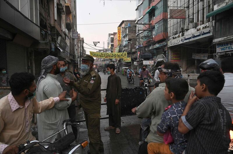 A policeman speaks with commuters in a closed market area in Lahore, Pakistan, after a nine-day shutdown to prevent a surge in coronavirus cases during Eid Al Fitr. AFP