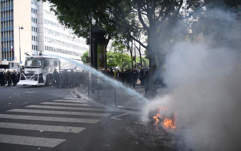 French anti-riot police officers use a water cannon to extinguish a motorbike on fire during clashes with demonstrators on the sidelines of the annual May Day rally in Paris. AFP