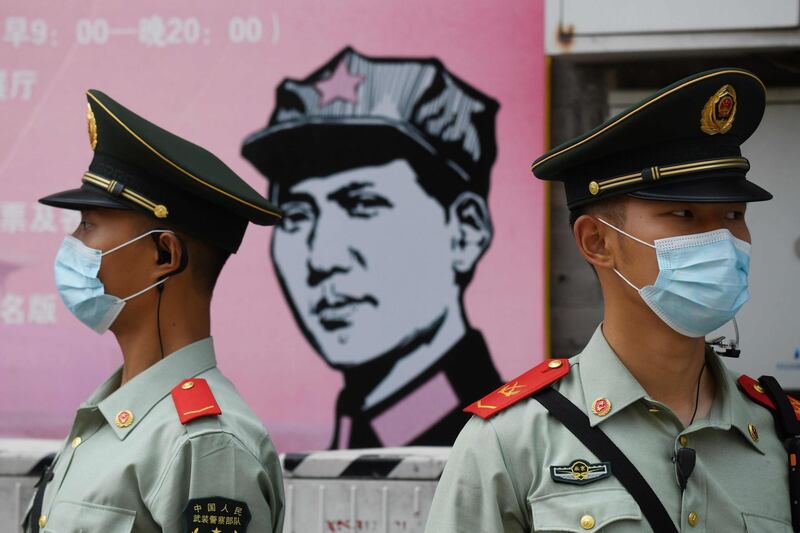 Paramilitary police officers stand guard in front of a poster of late communist leader Mao Zedong on a street south of the Great Hall of the People during the opening session of the National People's Congress (NPC) in Beijing on May 22, 2020. China moved to impose stringent new security laws on restive Hong Kong as its coronavirus-delayed parliamentary session opened on May 22 with a warning from Premier Li Keqiang of the "immense" challenges facing the world's second-largest economy. / AFP / GREG BAKER
