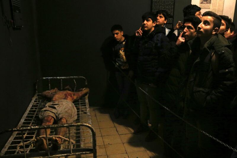 In this Jan. 7, 2019 photo, Iranian schoolboys look looks at an exhibition at a former prison run by the pre-revolution intelligence service, SAVAK, now a museum, where a wax mannequin of a prisoner is tied to a bed, in downtown Tehran, Iran. As Iran marks the 40th anniversary of its Islamic Revolution and the overthrow of the shah, those who suffered torture at the hands of the police and dreaded SAVAK still bear the scars. U.N. investigators and rights group say that even today, Iran tortures and arbitrarily detains prisoners. (AP Photo/Ebrahim Noroozi)