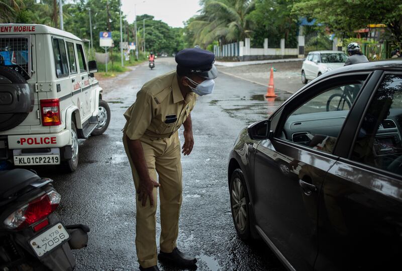 A policeman bends down to check the occupants of a car as he enforces a weekend lockdown to curb the spread of Covid-19 in Kochi, Kerala state, India.