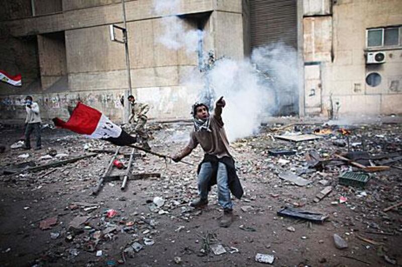 A protester points to an incoming tear gas canister as a fifth day of clashes continues to threaten November 28 elections.