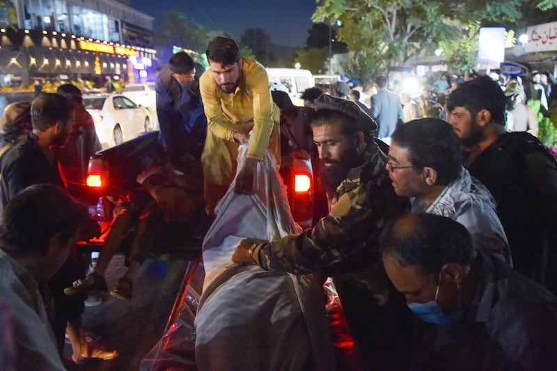 Volunteers and medical staff unload bodies from a pickup truck outside a hospital after two powerful explosions, which killed at least six people, outside the airport in Kabul on August 26, 2021. AFP