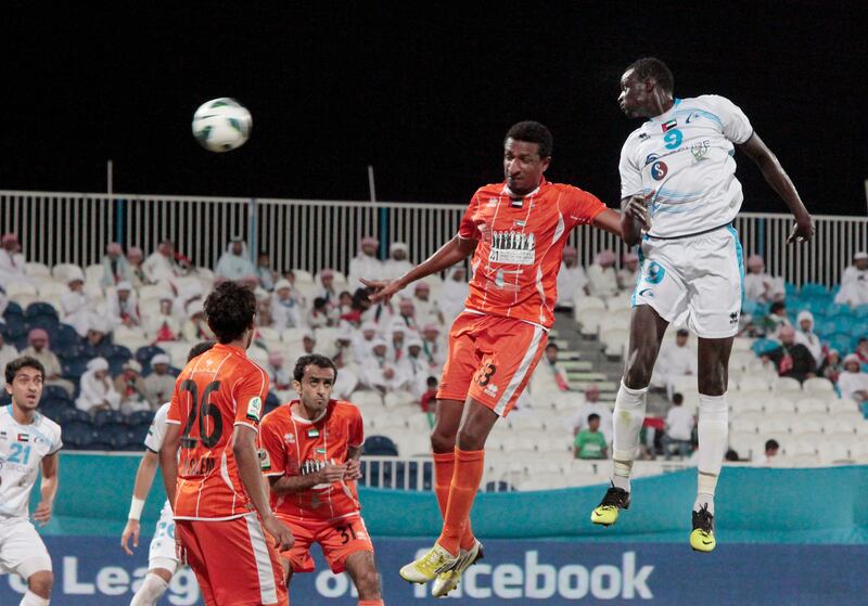 Abu Dhabi, United Arab Emirates - November 24, 2012.  Andre Senghor ( no 9 of Bani Yas ), and  Mousa Abdulrahman ( no 13 of Ajman, orange uniform ) on an aerial battle at team mates looks on, at the Etisalat Pro League football match.  ( Jeffrey E Biteng / The National )