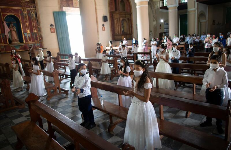 Children wearing protective face masks attend their First Communion ceremony at the Dulce Nombre de Jesus's Catholic church in the Petare neighbourhood of Caracas, Venezuela. AP