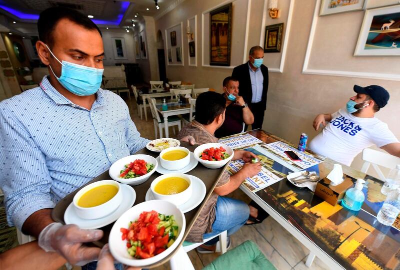 People eat at a restaurant in Dubai as measures begin to ease.However, precautions are still. inplace to protect diners. Karim Sahib / AFP