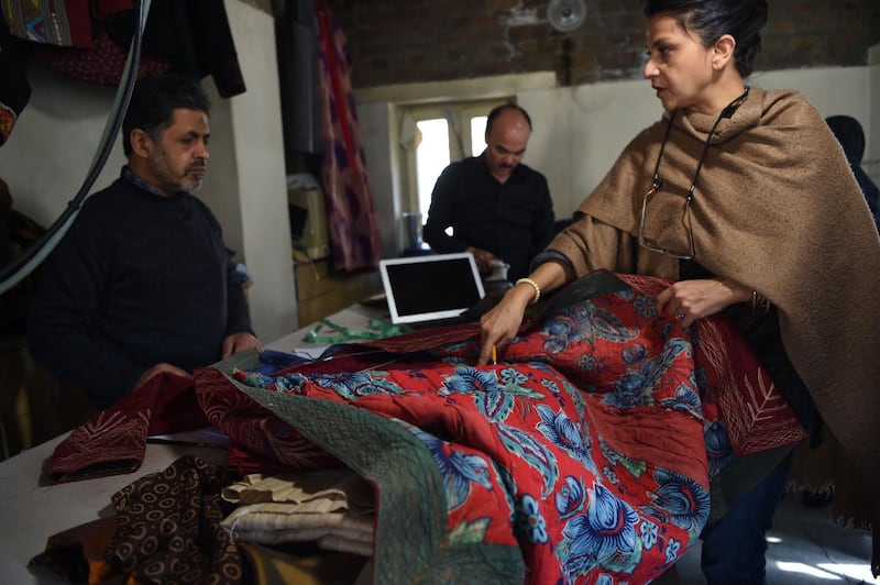 This photo taken on February 25, 2018 shows Afghan owner of Zarif Design House Zolaykha Sherzad (R) showing an older traditional chopan (coat) to her employees at the Zarif Design house in Kabul.
Cheap, Chinese-made nylon burkas are flooding Afghanistan's north as consumers turn to affordable, mass-produced fabrics -- but in Kabul a small, determined fashion house is fighting to preserve the traditional textiles once integral to Afghan culture.
 / AFP PHOTO / WAKIL KOHSAR / TO GO WITH Afghanistan-lifestyle-social-fashion,FEATURE by Anne Chaon