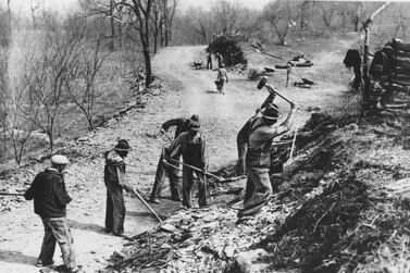 In this March 1936 picture, workers build a new farm-to-market road along Knob Creek in Tennessee. The New Deal was a try-anything moment during the Great Depression that remade the role of the federal government in American life. AP