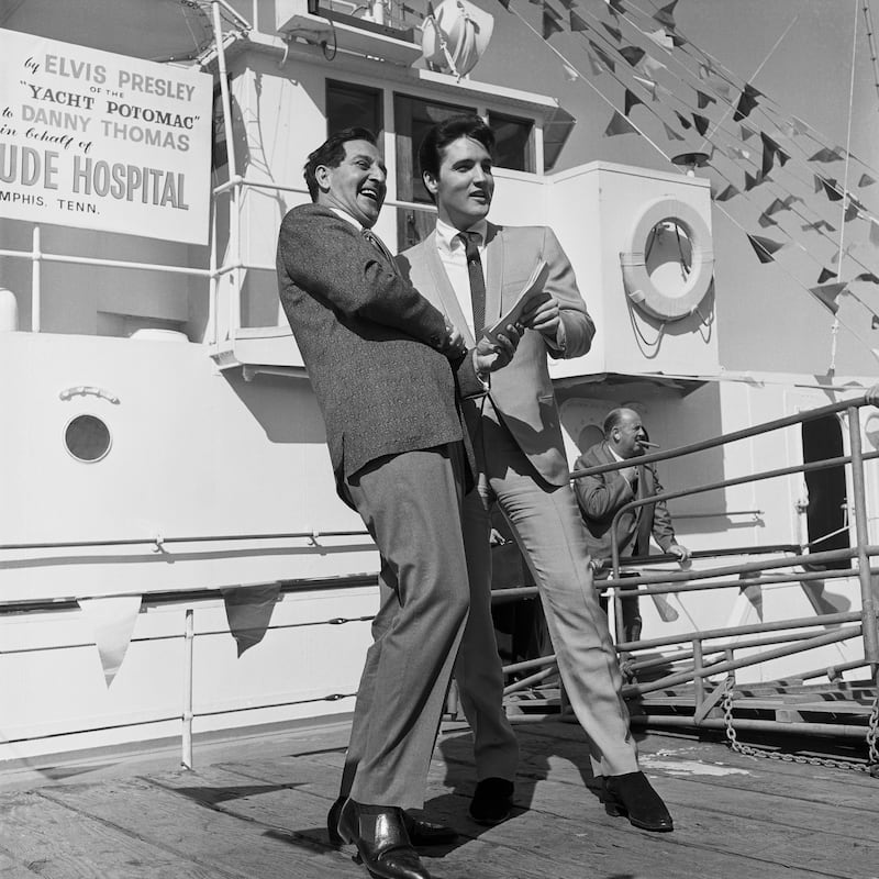 Elvis Presley (right) turns over the papers for the SS Potomac, former presidential yacht of the late President Franklin D Roosevelt, to Thomas. Photo: Bettmann Archive