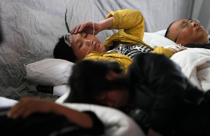 epa03670894 A Chinese woman injured in the earthquake gestures as she lies with other patients in a hospital tent in Lushan County of Ya'an,Sichuan Province, China, 21 April 2013. At least 180 people died and thousands were injured in an earthquake that struck China's south-western province of Sichuan, officials said 21 April 2013.  EPA/HOW HWEE YOUNG *** Local Caption ***  03670894.jpg