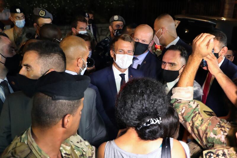 French President Emmanuel Macron, center, speaks with an anti government protester after his visit to the Lebanon's diva Fairouz, one of the Arab world's most popular singers, in Rabieh, north Beirut, Lebanon, Monday, Aug. 31, 2020. Macron returned to Lebanon on Monday, Aug. 31, 2020 a country in the midst of an unprecedented crisis, for a two-day visit and a schedule packed with political events and talks aimed at charting a way out for the country. For his first meeting, Macron chose to see Lebanon's No. 1 diva Fairouz, a national symbol and one of the rare figures in Lebanon. (AP Photo/Bilal Hussein)