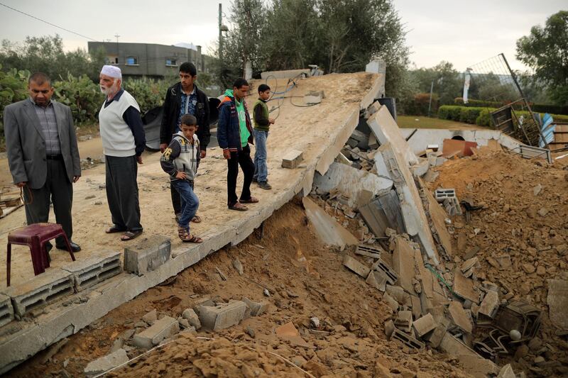 Palestinians stand on the remains of a building. Reuters