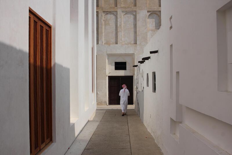 R028FW A Bahraini man wearing dishdash, guthra, and aghal walking along a narrow alley on the Pearl Trail, old Muharraq, Kingdom of Bahrain. Alamy