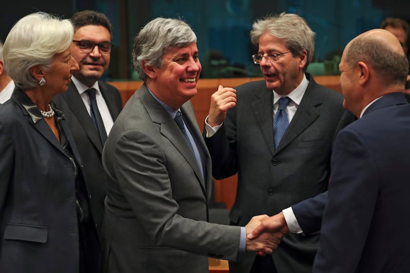 FILE - In this Monday, Jan. 20, 2020 file photo Eurogroup President Mario Centeno, center, shakes hands with German Finance Minister Olaf Scholz, right, next to European Central Bank President Christine Lagarde, left, Cyprus' Economy Minister Constantinos Petrides, second left, and European Commissioner for Economy Paolo Gentiloni, second right, during a meeting of European Union Finance Ministers in Eurogroup format at the Europa building in Brussels. Governments from the 19 countries that use the euro overcame sharp differences to agree Thursday on measures that could provide more than a half-trillion euros ($550 billion) for companies, workers and health systems to cushion the economic impact of the virus outbreak. Mario Centeno, who heads the finance ministers' group from euro countries, called the package of measures agreed upon "totally unprecedented... Tonight Europe has shown it can deliver when the will is there." (AP Photo/Francisco Seco, File)
