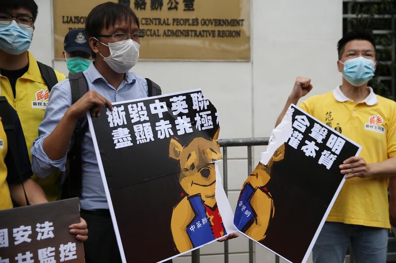 epa08440322 Local district councillors tear a poster, depicting Winnie the Pooh tearing up the 1984 Sino-British Joint Declaration, during a protest against a newly proposed national security law outside the China Liaison Office in Hong Kong, China, 24 May 2020. Beijing unveiled a resolution at the opening of its annual legislative sessions that will bypass Hong Kong's legislature to outlaw acts of secession, subversion and terrorism in Hong Kong.  EPA/JEROME FAVRE