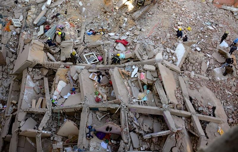 People and rescuers gather around the rubble of a building that collapsed in the Egyptian capital Cairo. AFP