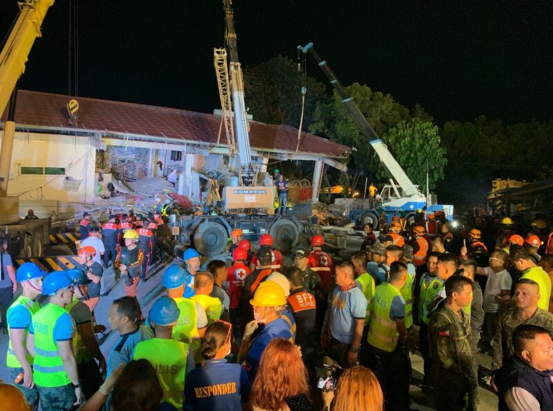 Workers join rescue operations for people still trapped inside a collapsed building at Porac town, Pampanga province, northern Philippines Monday, April 22, 2019. A strong 6.1 magnitude earthquake in the north Philippines on Monday trapped some people in a collapsed building, damaged an airport terminal and knocked out power in at least one province, officials said. (AP Photo/Bullit Marquez)