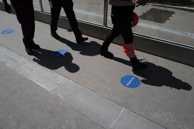 Shadows of Tour Eiffel workers are cast on the access lane with social distancing stickers during a presentation of the security measures at the Eiffel Tower in Paris. AP