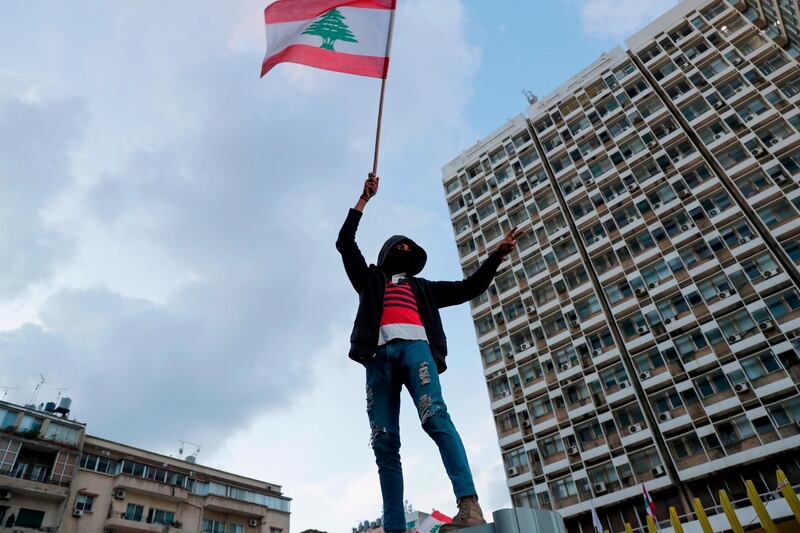 A Lebanese demonstrator waves the national flag during a demonstration outside the Electricite du Liban (Electricity Of Lebanon) national company headquarters in the Lebanese capital Beirut on January 11, 2020. Hundreds protested across Lebanon to denounce a crippling economic crisis and the political deadlock that has left the country without a government for over two months. Chanting anti-government slogans in the capital Beirut, the northern city of Tripoli and the southern city of Nabatieh, they also denounced a class of political leaders they deem incompetent and corrupt. / AFP / ANWAR AMRO
