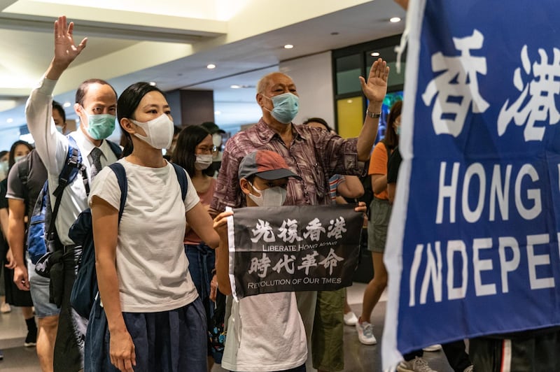Pro-democracy supporters hold banners and shout slogans as they march in a shopping mall during a lunch protest in Hong Kong, China.Getty Images