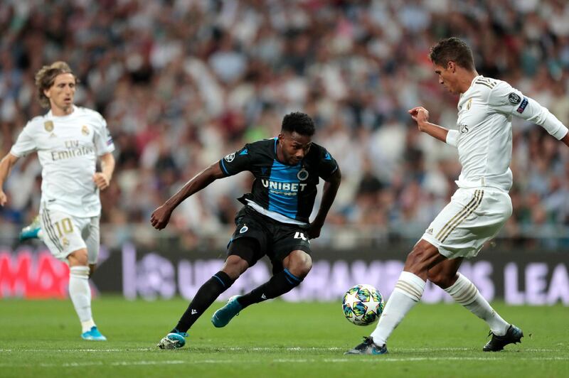 Brugge's Emmanuel Dennis, center, controls the ball by Real Madrid's Raphael Varane, right, during the Champions League group A soccer match between Real Madrid and Club Brugge, at the Santiago Bernabeu stadium in Madrid. AP Photo