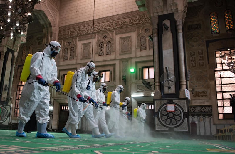 Workers wearing protective suits spray disinfectant on the floor of Al Fateh Mosque in Cairo, Egypt. Muslims around the world are preparing for the second Ramadan of the pandemic. EPA