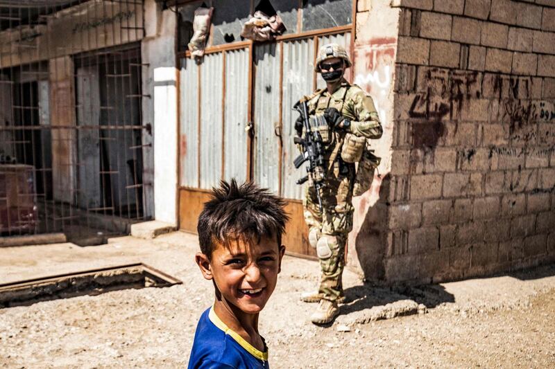 A US soldier looks on as a boy smiles at the camera during a US military patrol in Rmelan, in Syria's north-eastern Hasakeh province. AFP