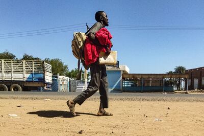 A man displaced by the conflict in Sudan walks with his belonging along a road in Wad Madani south of the capital Khartoum. AFP