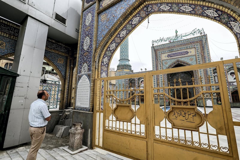 A man stands by the closed gate outside the Imamzadeh Saleh in the Iranian capital Tehran's Shemiran district on April 25, 2020 during the Muslim holy month of Ramadan, as all mosques and places of worship are closed due to the COVID-19 coronavirus pandemic. (Photo by ATTA KENARE / AFP)