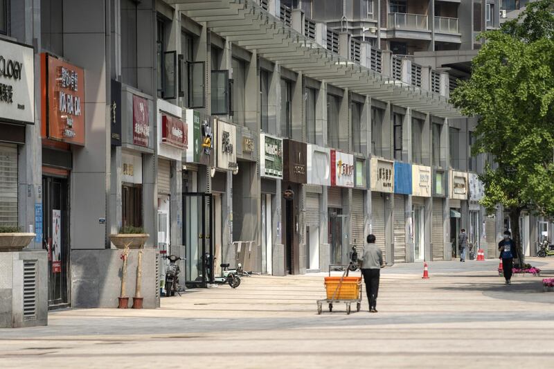 A pedestrian pulls a cart past closed stores on a near-empty street in Wuhan, China. The lifting on April 8 of the unprecedented lockdown on Wuhan -- where the virus first emerged -- was a milestone. Stringent nationwide restrictions in China meant the world's second-largest economy recorded its deepest contraction in decades over the first quarter. Bloomberg