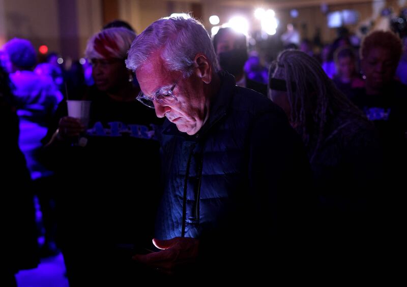An anxious voter refreshers his browser to get the results as Mr Warnock's party continues behind him. Getty / AFP