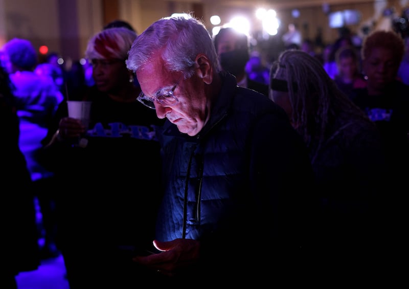 An anxious voter refreshers his browser to get the results as Mr Warnock's party continues behind him. Getty / AFP
