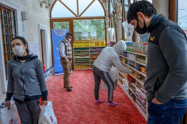 People take their need on April 21, 2020, in the Sariyer district of Istanbul, at the entrance of the Dedeman mosque where the racks reserved for shoes of the Muslim faithful is instead loaded with food. AFP