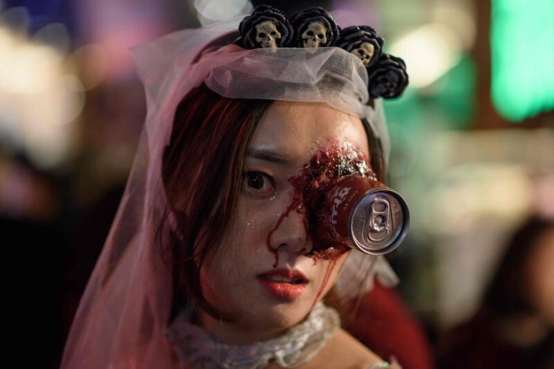 A reveller wearing Halloween make-up poses for a photo in the popular nightlife district of Itaewon in Seoul.  AFP