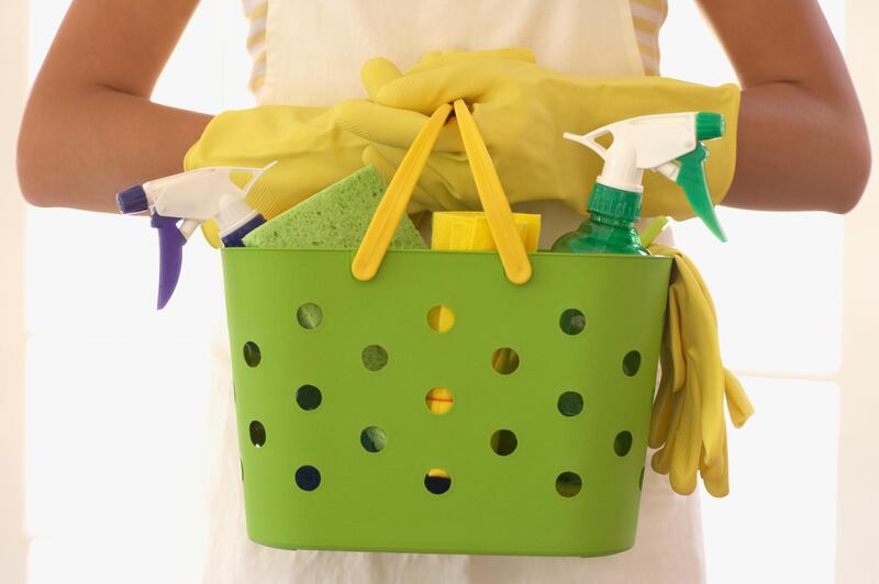 Hispanic woman carrying cleaning supplies. Getty Images