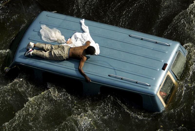 A man clings to the top of a vehicle before being rescued by the U.S. Coast Guard from the flooded streets of New Orleans, in the aftermath of Hurricane Katrina, in Louisiana on September 4, 2005. Robert Galbraith / Reuters