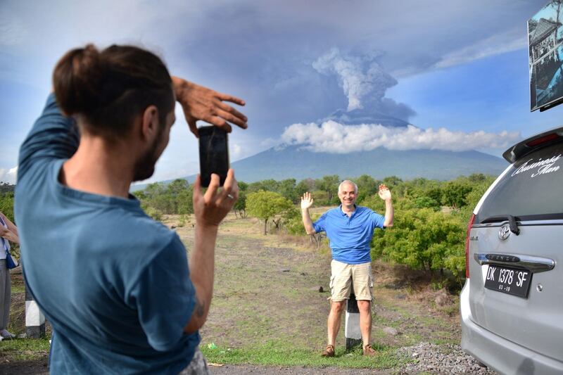A foreign tourist takes pictures in front of Mount Agung erupting seeb from Kubu sub-district in Karangasem Regency, on Indonesia's resort island of Bali on November 27, 2017.  Sonny Tumbelaka / AFP