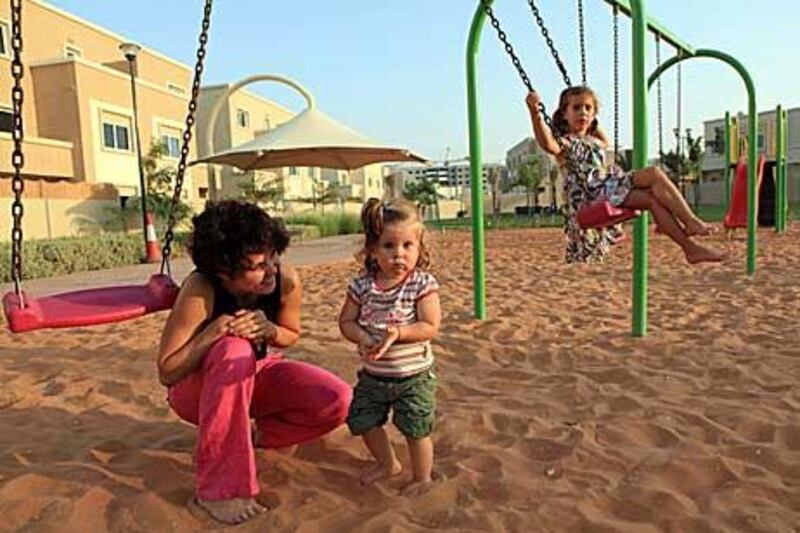 Joanne Rajch plays with her children Gloria and Wiktoria Sinczak, aged one and five, in grounds near their home  in Al Reef Villas. “It’s hard to get a flat in the city near a park,” said Mrs Rajch.