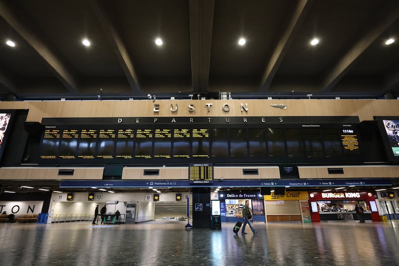 A traveller walks under the departures board of an empty Euston Station in London, as rail workers strike. Getty Images