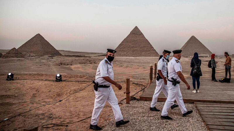 Policemen walk along a promontory overlooking (R to L) the Great Pyramid of Khufu (Cheops), the Pyramid of Khafre (Chephren), and the Pyramid of Menkaure (Menkheres) at the Giza Pyramids necropolis on the southwestern outskirts of the Egyptian capital Cairo before an official ceremony launching the trial operations of the site's first environmentally-friendly electric bus and restaurant as part of a wider development plan at the necropolis.   AFP