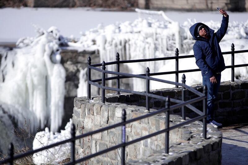 A visitor takes a selfie in front of the Paterson Great Falls National Historical Park in New Jersey. Julio Cortez / AP Photo