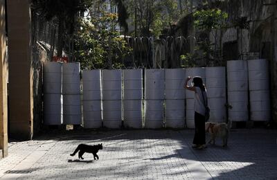 A woman walks with her dog next to a barricade made of barrels at the UN-controlled buffer zone in Nicosia, Cyprus, April 27, 2021. REUTERS/Yiannis Kourtoglou