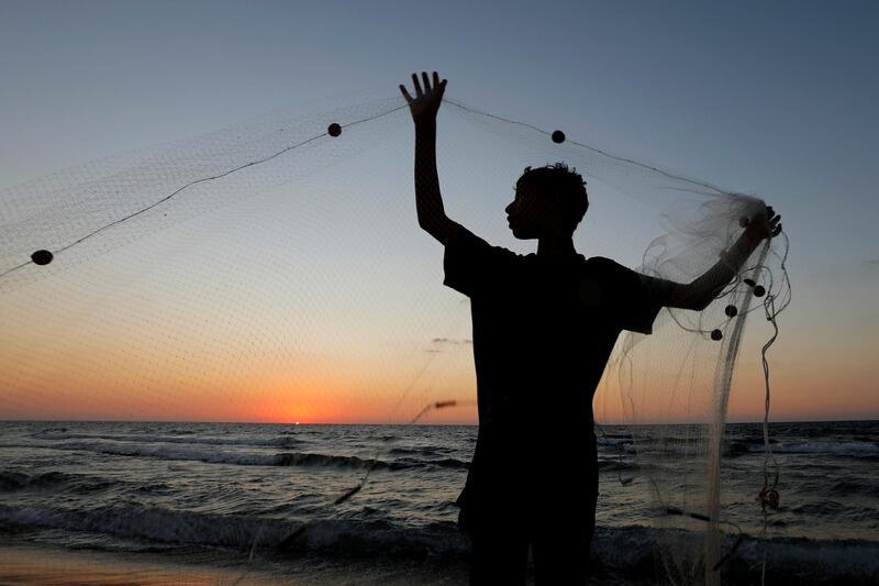 A Palestinian fisherman repairs his net at a beach in the northern Gaza Strip. Reuters