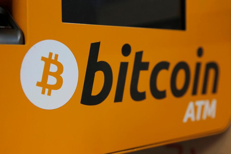 FILE- In this Dec. 21, 2017, file photo, a Bitcoin logo is shown is displayed on an ATM in Hong Kong. Google says it is going to ban advertisements for cryptocurrencies such as bitcoin, as well as related content like trading advice and cryptocurrency wallets. (AP Photo/Kin Cheung, File)
