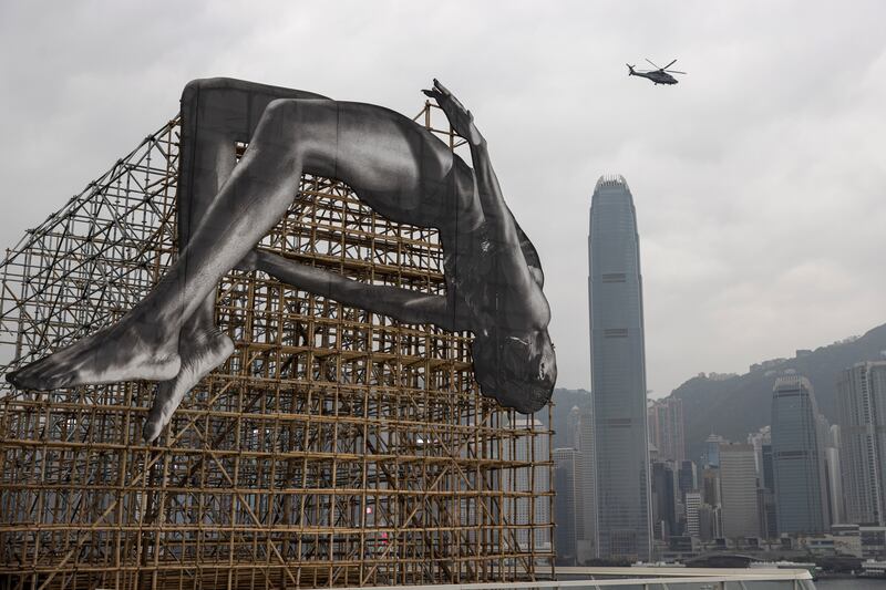 A helicopter flies near the art piece 'GIANTS: Rising Up' at Harbour City in Hong Kong.  EPA