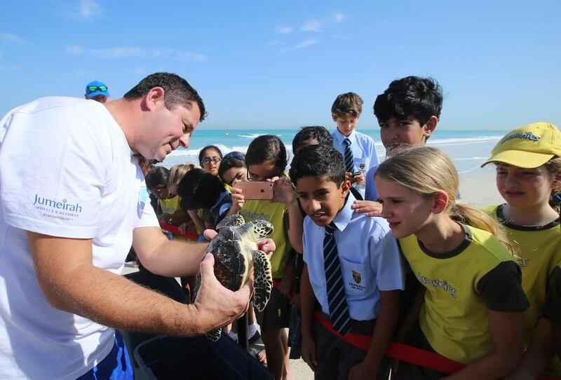 David Robinson, assistant operations manager at Burj Al Arab Aquarium, tells children from Cranleigh School about turtles on Wednesday at Saadiyat Beach Club in Abu Dhabi. Ravindranath K / The National